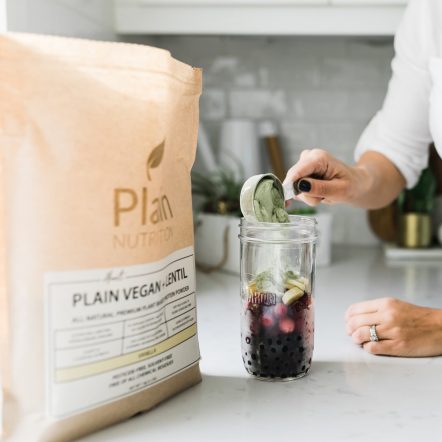 Almost Plain Vegan Plus Lentil Vanilla Scoop Pouring Into Shake